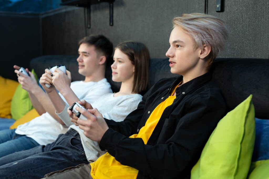Group of friends of teenagers, playing video games on a console in a game club.